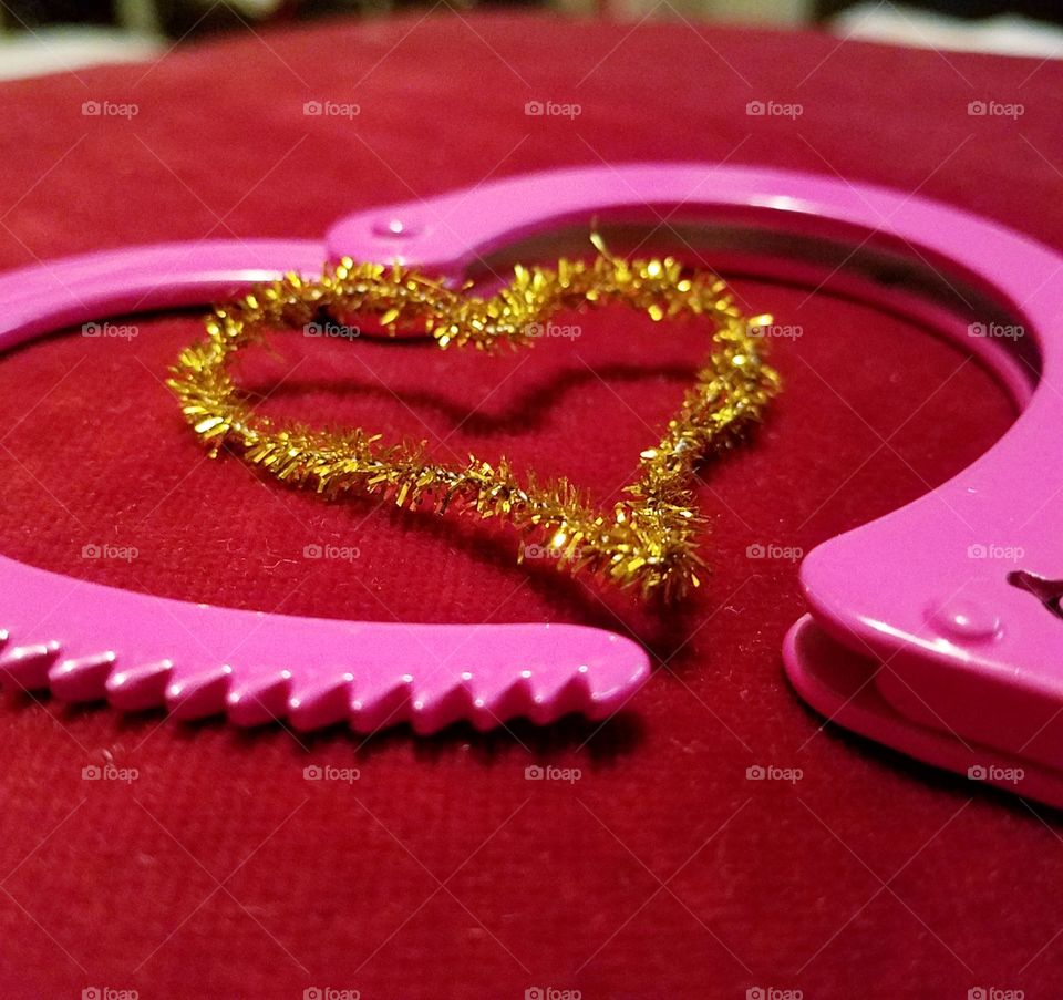 gold heart and pink handcuff on red velvet