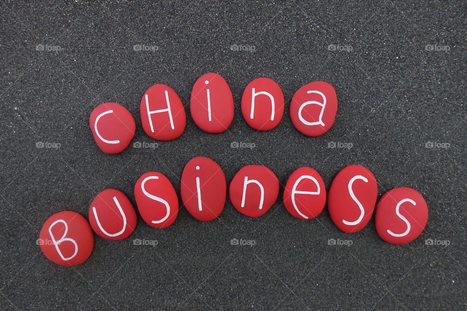 China Business text with red colored stones over black volcanic sand