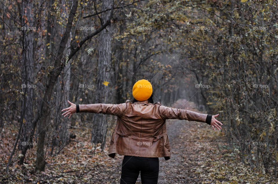 Woman in the autumn forest, yellow hat, hands raised up