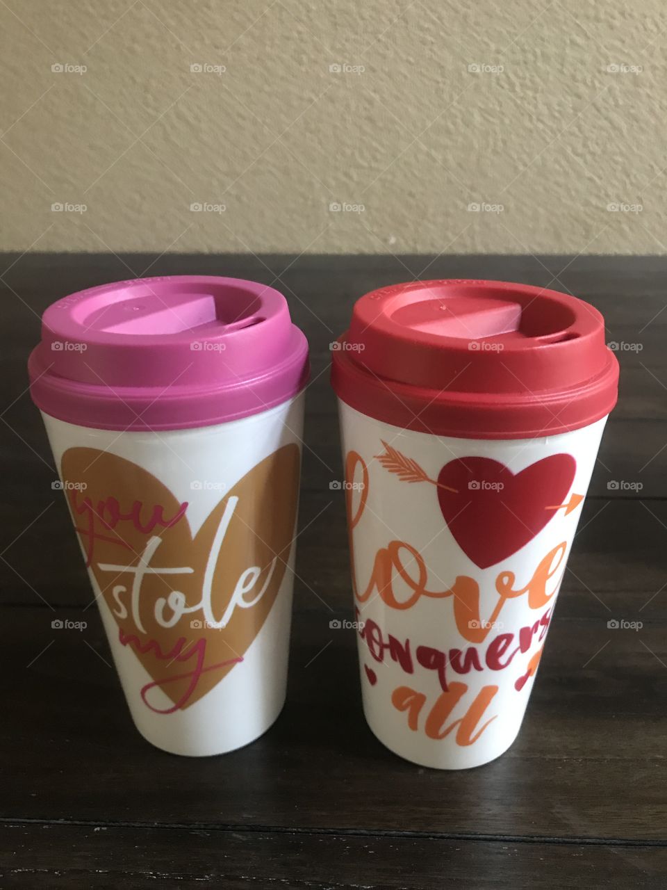 Two Valentine’s Day pink and red coffee mugs one saying love conquers all and the other saying you stole my heart. USA, America