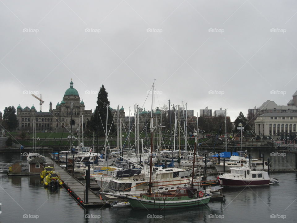 Boats in harbour with a grey, moody sky with grand building in the background 
