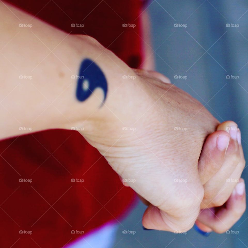 Mother with half of yin yang tattoo and her child holding hands 