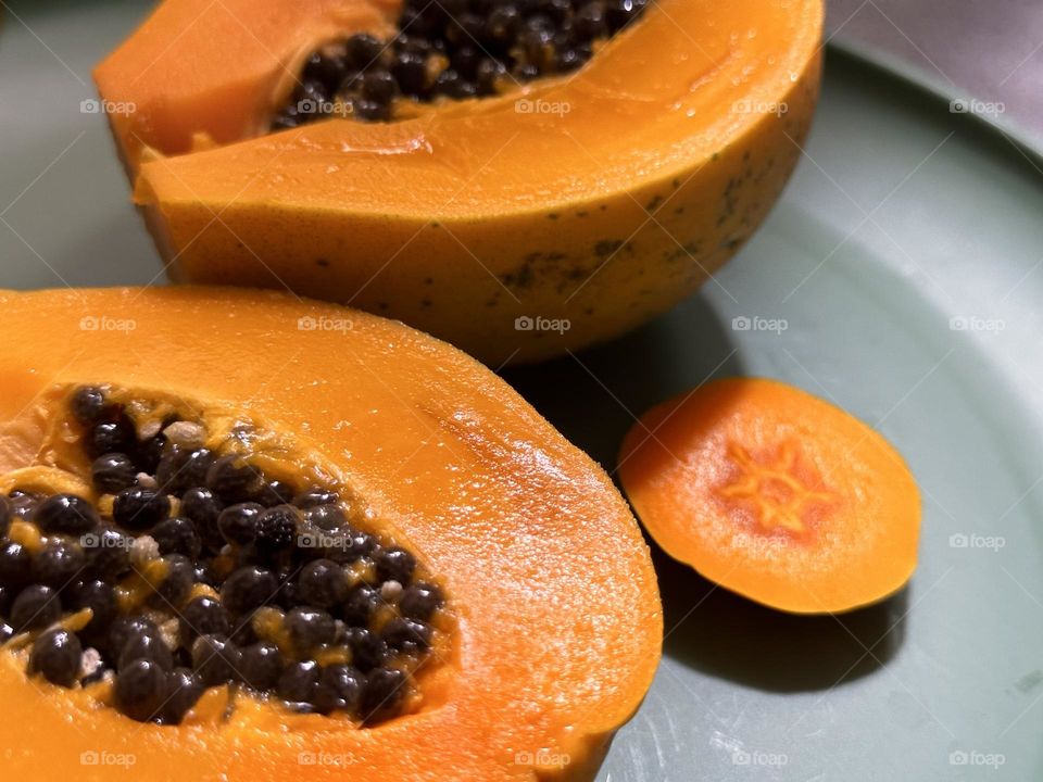 Ripe papaya right from the tree,sliced in half with the seeds still in, on a grayish green plate