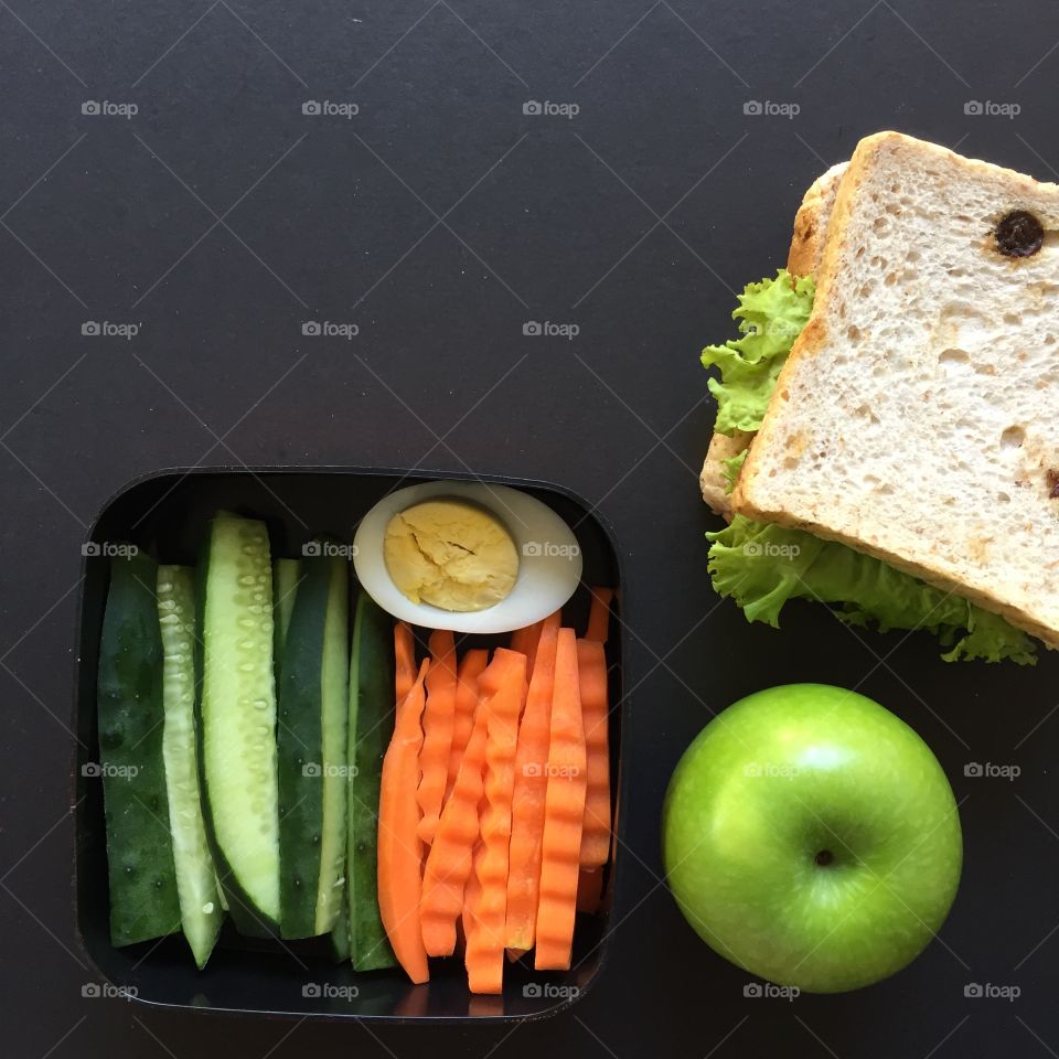 Lunchbox with carrots cucumber sandwich and an apple