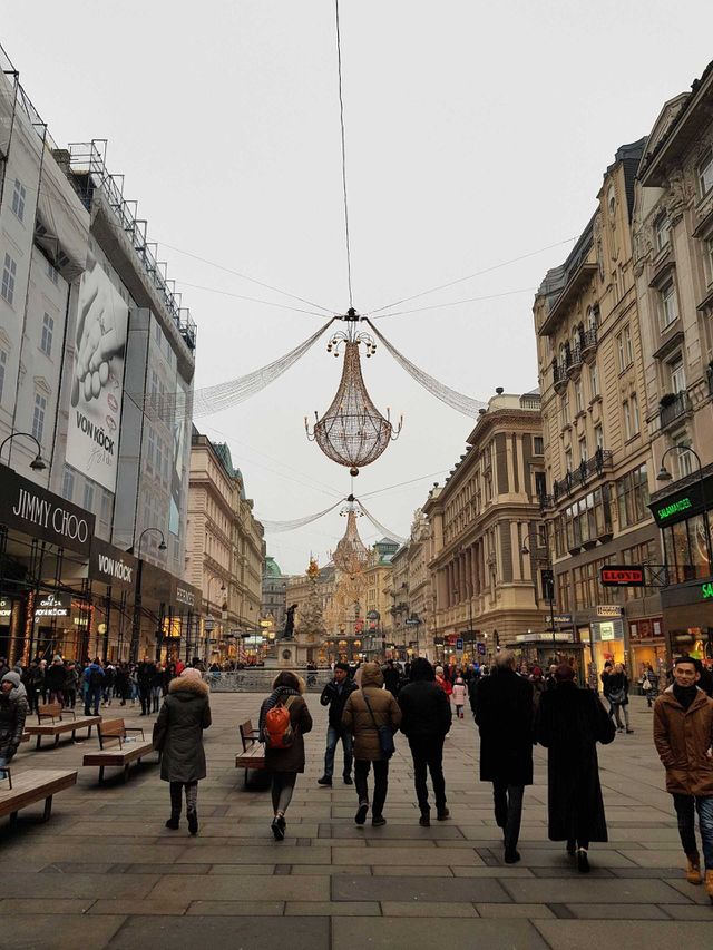 Photograph taken on January 1st in Wien, Austria. It features people hugging their coats, walking in the freezing cold, and the pretty Christmas lights and architecture of one of the most magical cities in Europe