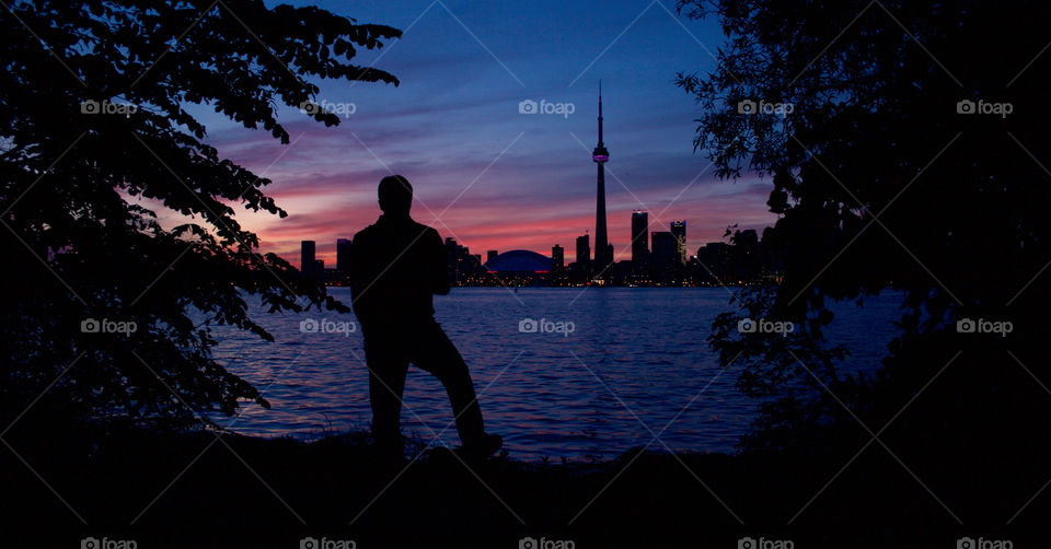 a man looks at the skyline of Toronto at dusk