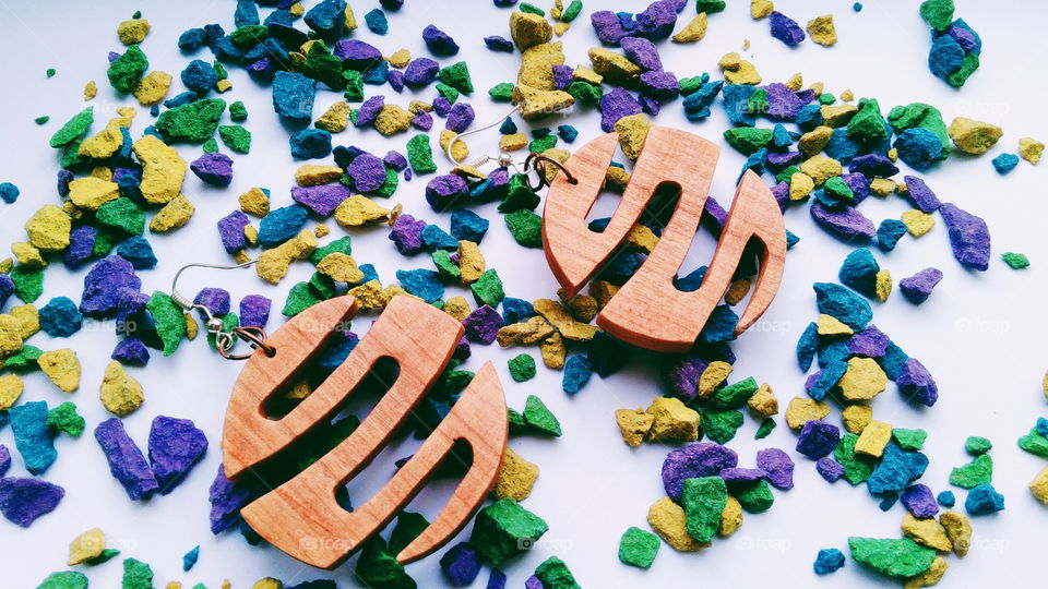 earrings made of wood on the background of multi-colored stones