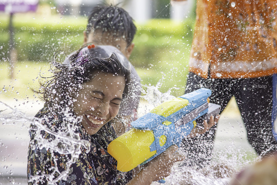 Asian woman holding a water gun play Songkran festival or Thai new year in Thailand.