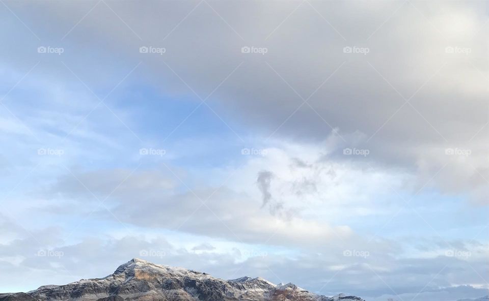 A photo of a snow covered mountains and clouds.