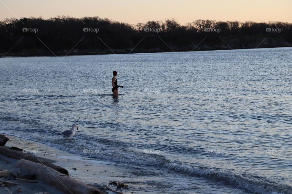 Woman dipping in cold ocean 