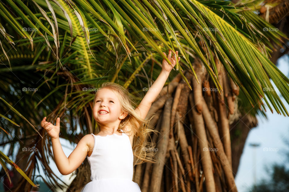 Little girl with blonde hair and palm tree