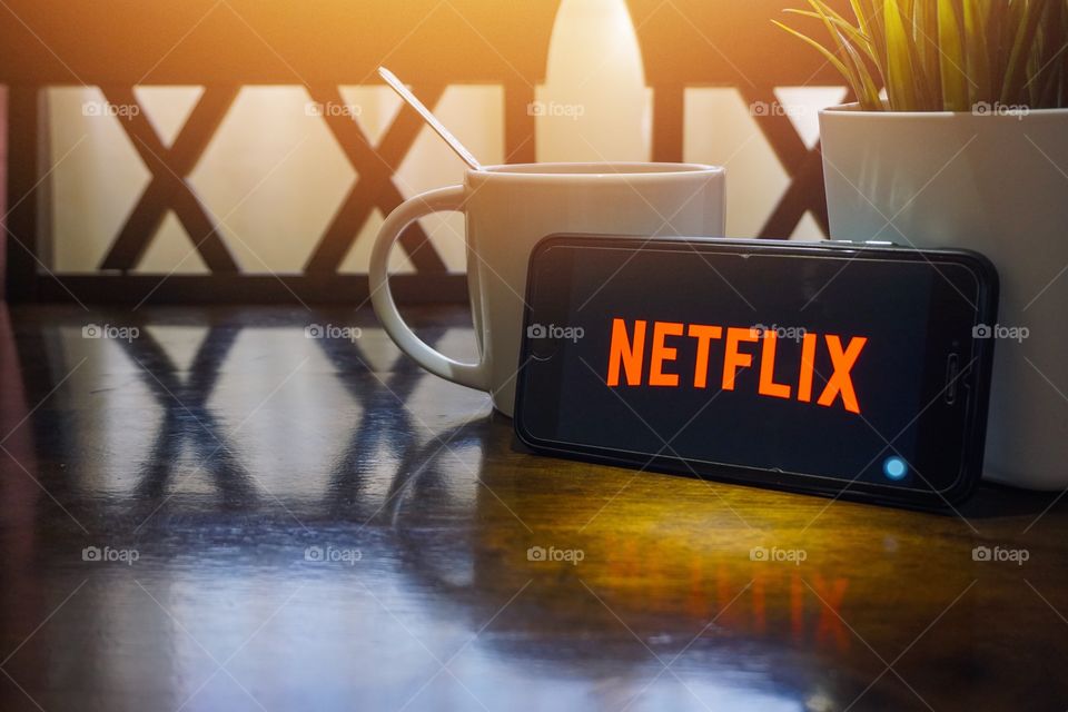 Kuala Lumpur, Malaysia - June 16, 2018:  Smartphone displaying word Netflix on wooden table with selective focus and crop fragment