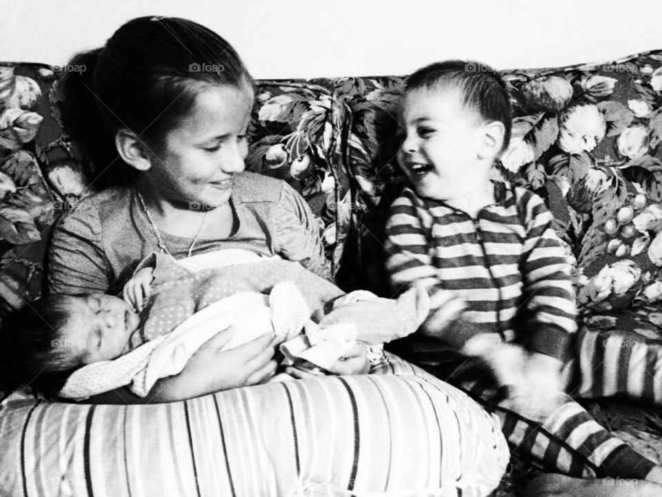 Big sister and brother holding baby sitter 