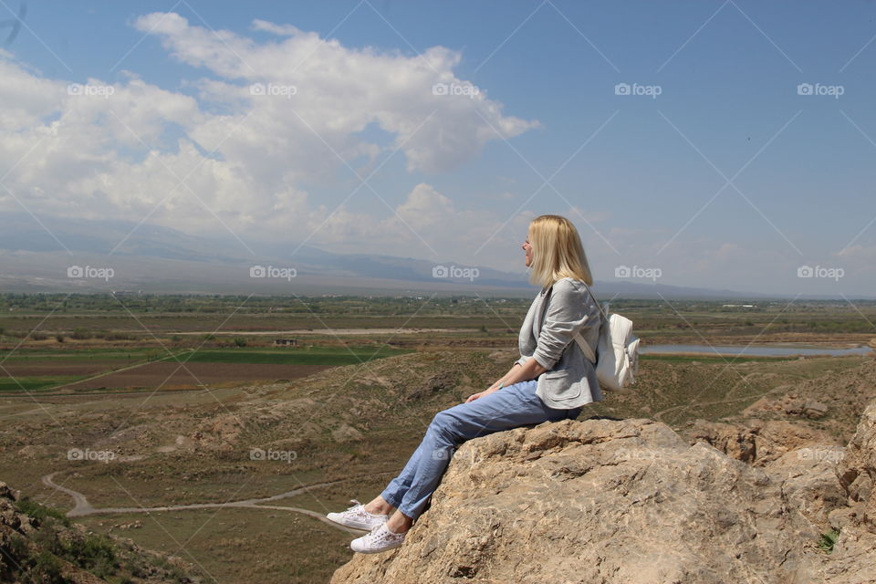 blonde girl sitting by the stone 