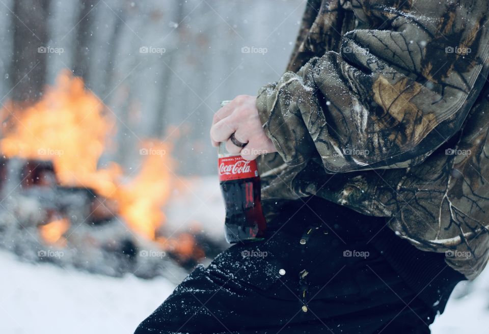 Tending a fire while enjoying Coca Cola