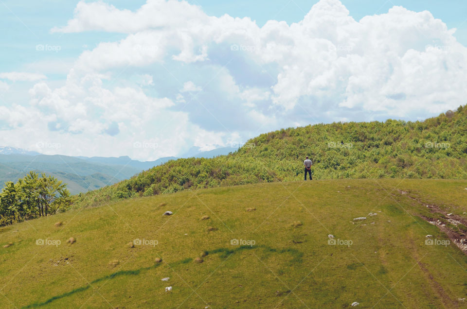 A man on the mountain looking into distance. What was he thinking about? He was probably just enjoying the view. 