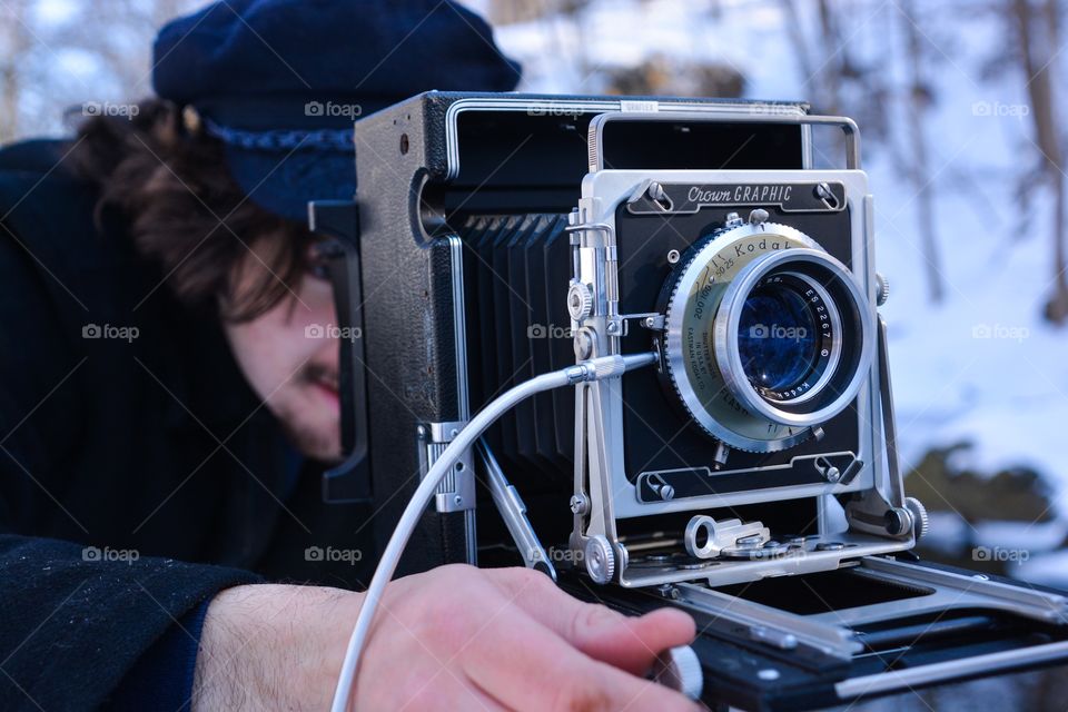 A man uses the old fashion photography equipment of a film camera to capture his image 