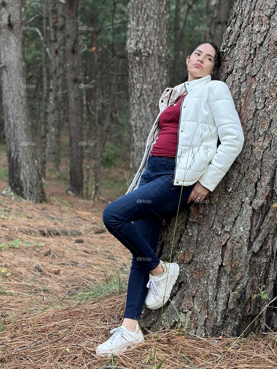 Portrait of woman leaning on a tree at the middle of the forest, while looks the horizon.