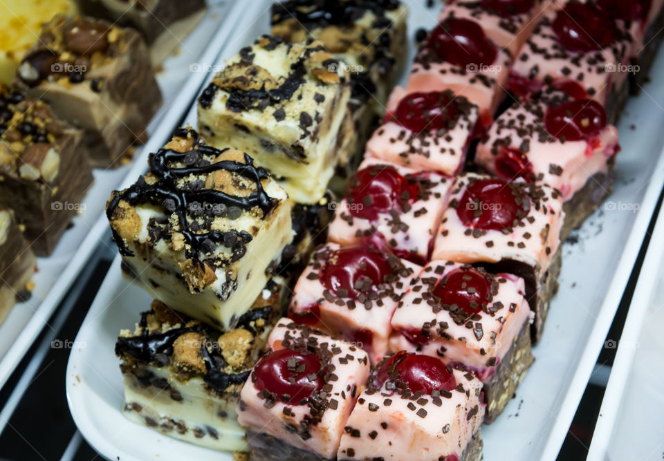 Bite size pieces of Vanilla, cherry and gourmet chocolate fudge squares on serving plate with chocolate sprinkles and cherry on top luxury dessert photography 