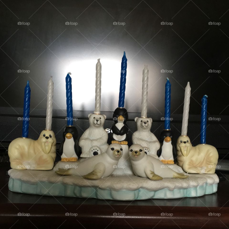 Hanukkah decorative menorah in the form of a handcrafted ceramic sculpture with a polar theme consisting of a snowcovered iceberg populated with polar animals (penguins. polar bears, walrus) which serve as 9 candle holders + 2 seal figurines in front