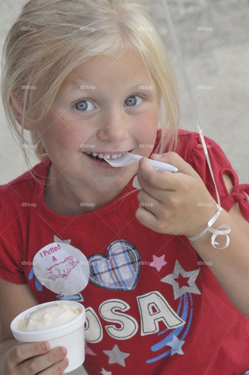Young blonde girl enjoying some ice cream.  