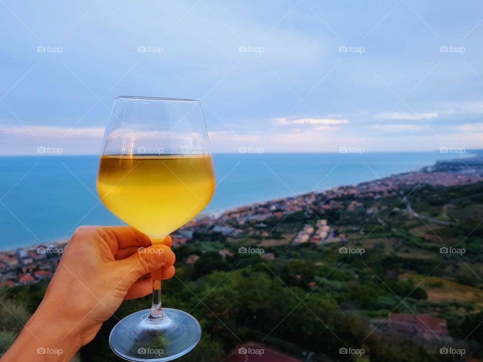 goblet of white wine brought up with the sea behind it