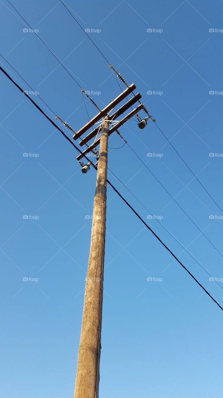 wooden utility pole with power lines and blue sky background