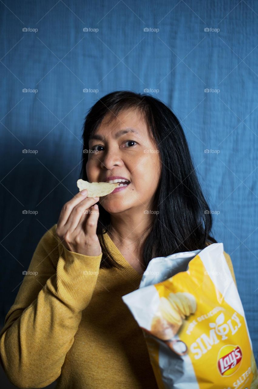 Portrait of a woman eating potato chips 