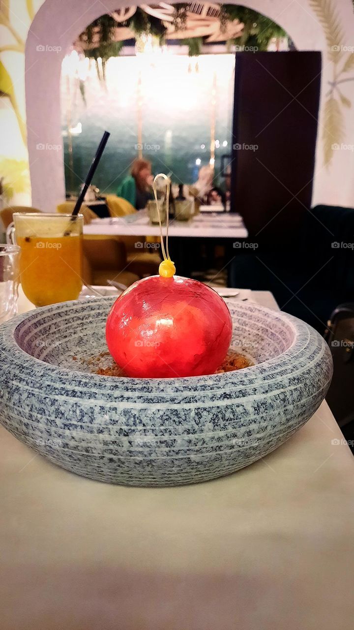 Dessert in the form of a red Christmas tree toy next to hot sea buckthorn tea