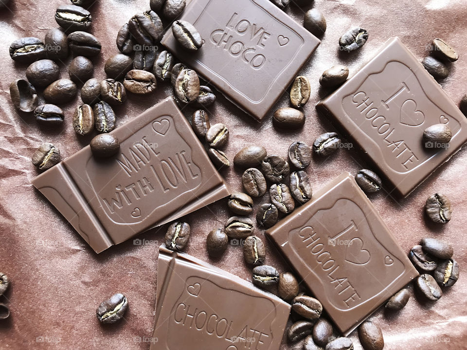 Bars of milk chocolate on brown paper background with coffee beans 