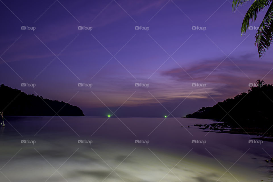 The beauty of the sunset in the sea and the light from the fishing boat.