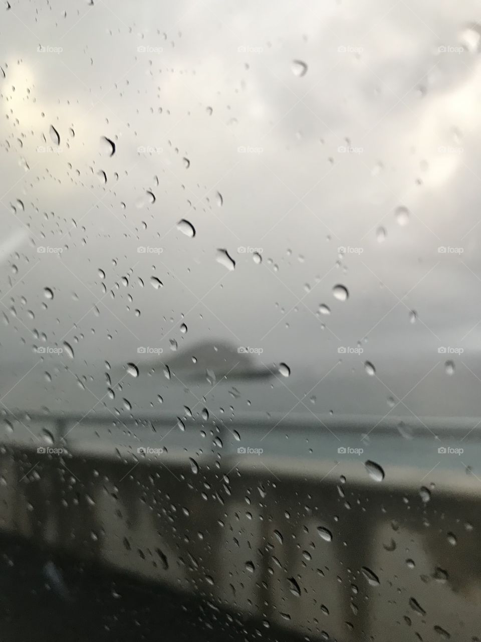 Close up of raindrops on window with rabbit island there in background 