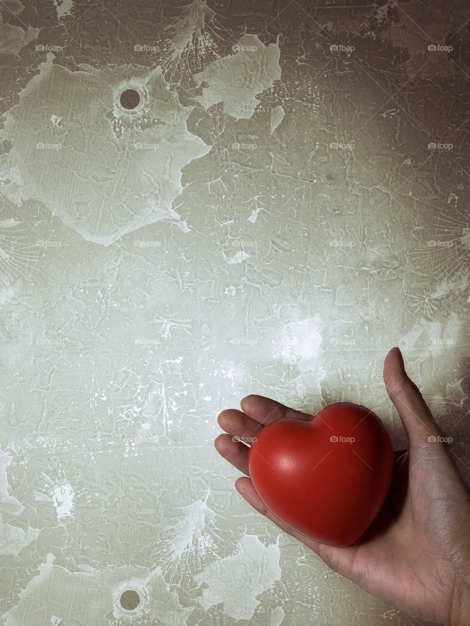 A lady holding a heart shaped against grunge background.