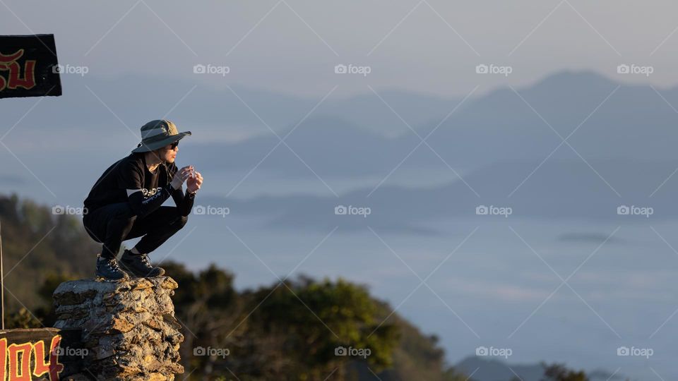 A tourist squatting on the edge facing ocean of mist in Chiangrai Thailand