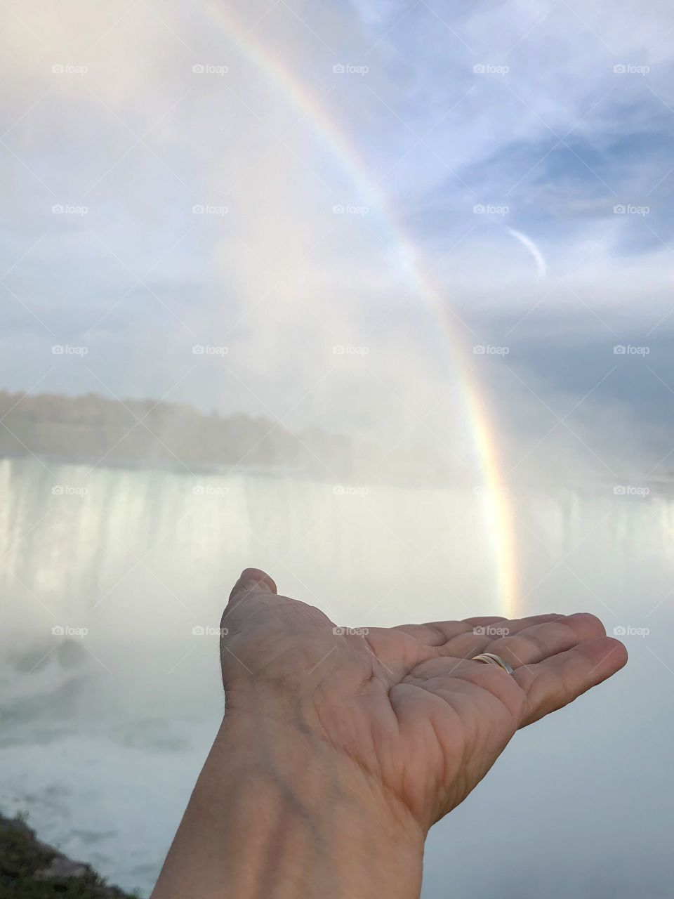 A hand pretending to get a rainbow in Niagara Falls