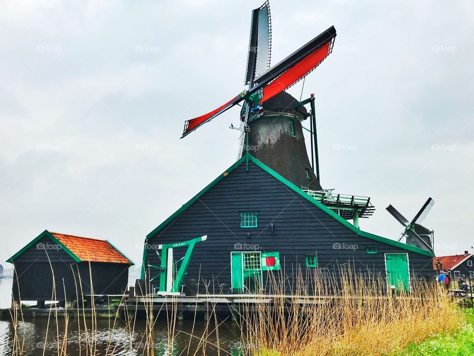 Windmill and water canal in Zaans Schans , Netherlands 