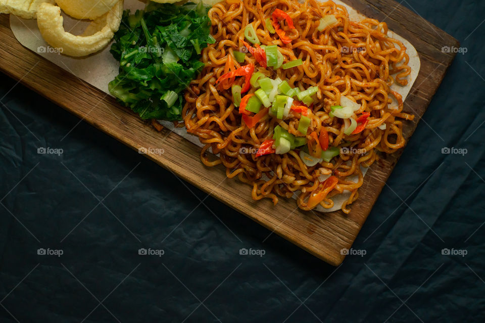 Fried Instant Noodles with vegetables on wooden plate