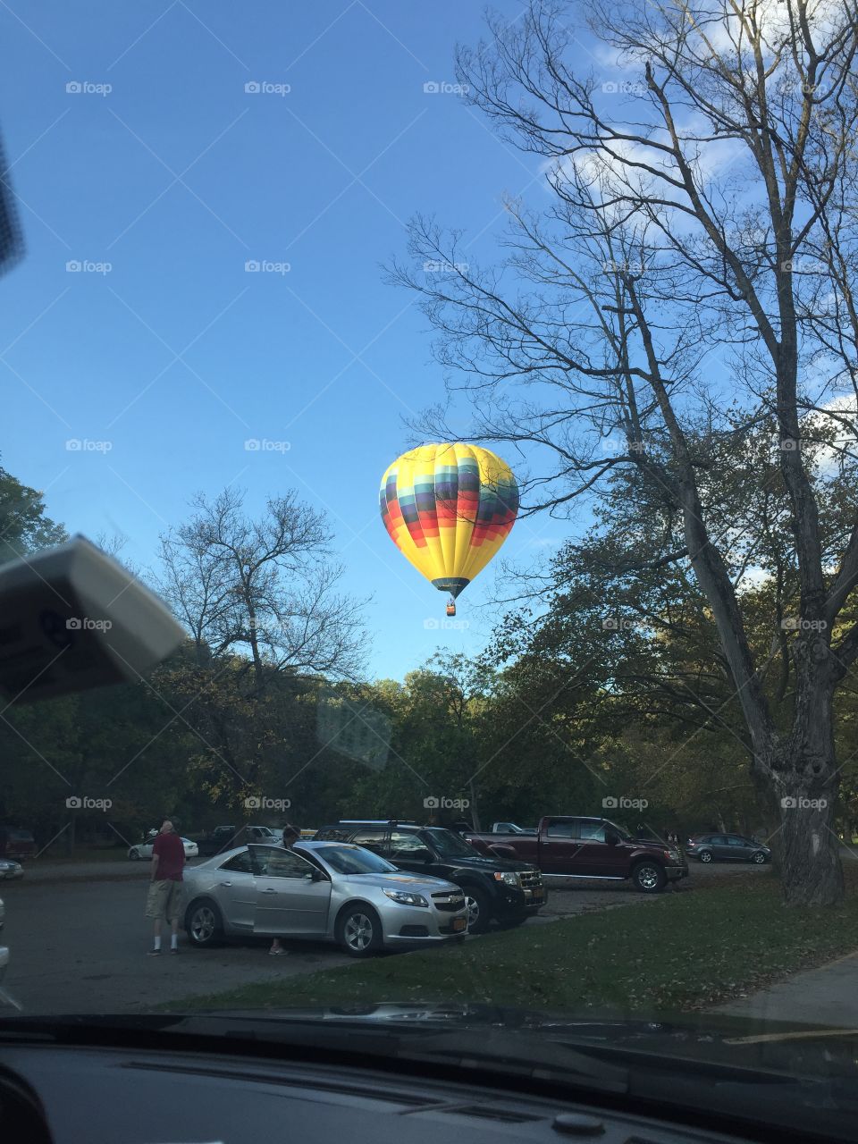 Hot air balloon floats over autumn trees