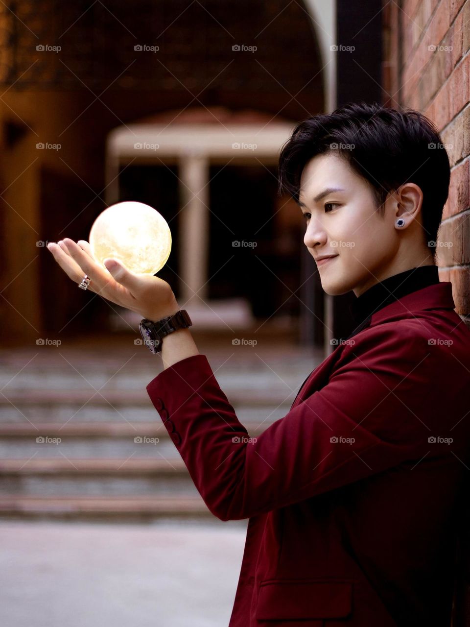 This is a picture with a young Hong Kong man in red blazer, holding a full moon model in his hand, showing the way how Chinese treats Mid-Autumn Festival. Also showing the colors of autumn!