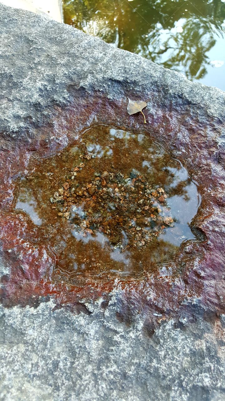 hole on cement with water in it with rocks