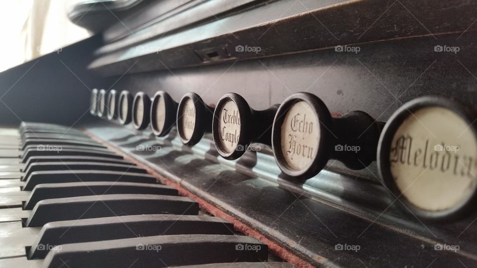 Close up of knobs and keys on an antique pump organ