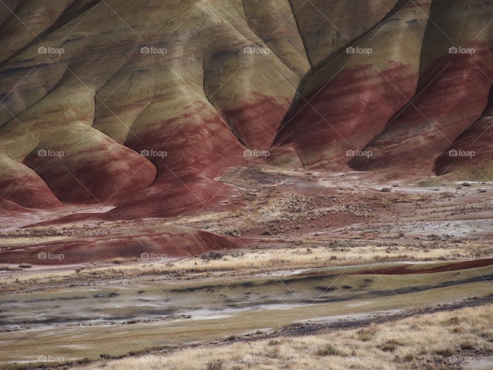 The incredible beauty of the red, gold, and browns of the textured Painted Hills in Eastern Oregon on a bright sunny day.