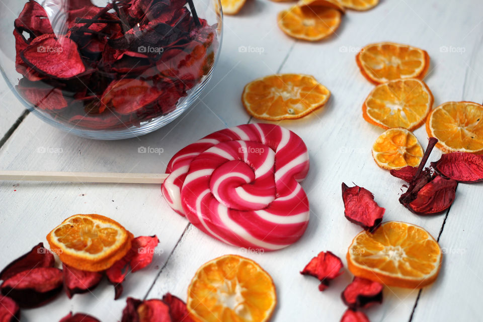 Rose petals with candy and orange fruits