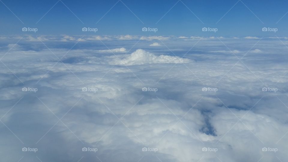 Flying high above puffy white clouds and blue sky