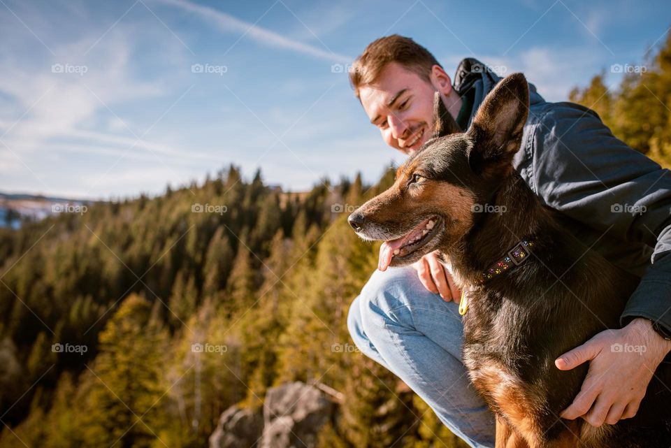 Man on a hike with his dog admiring the view over a cliff