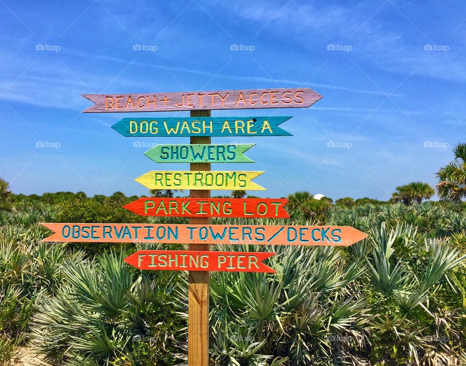 Brightly painted wooden beach sign pointing direction to different areas of interest 