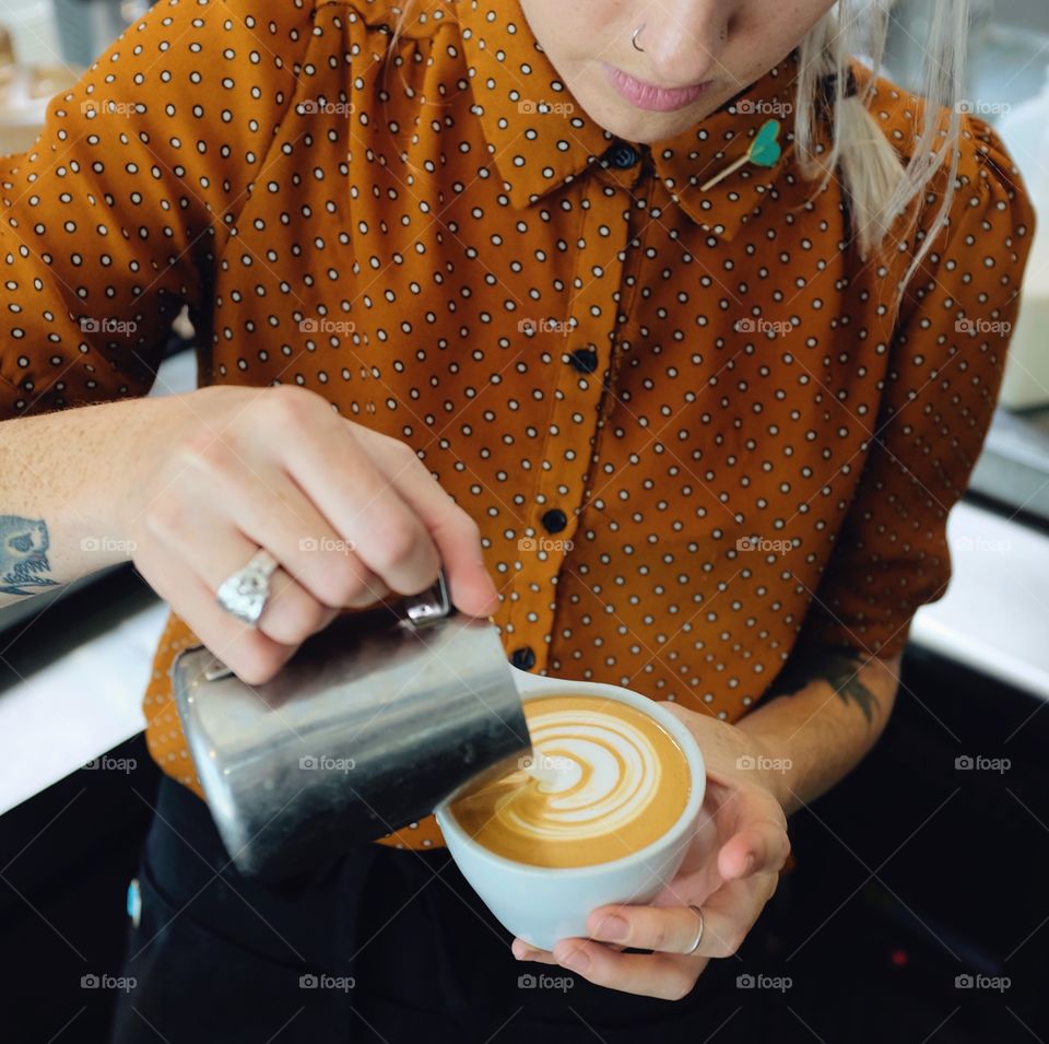 Women barista pouring latte art.