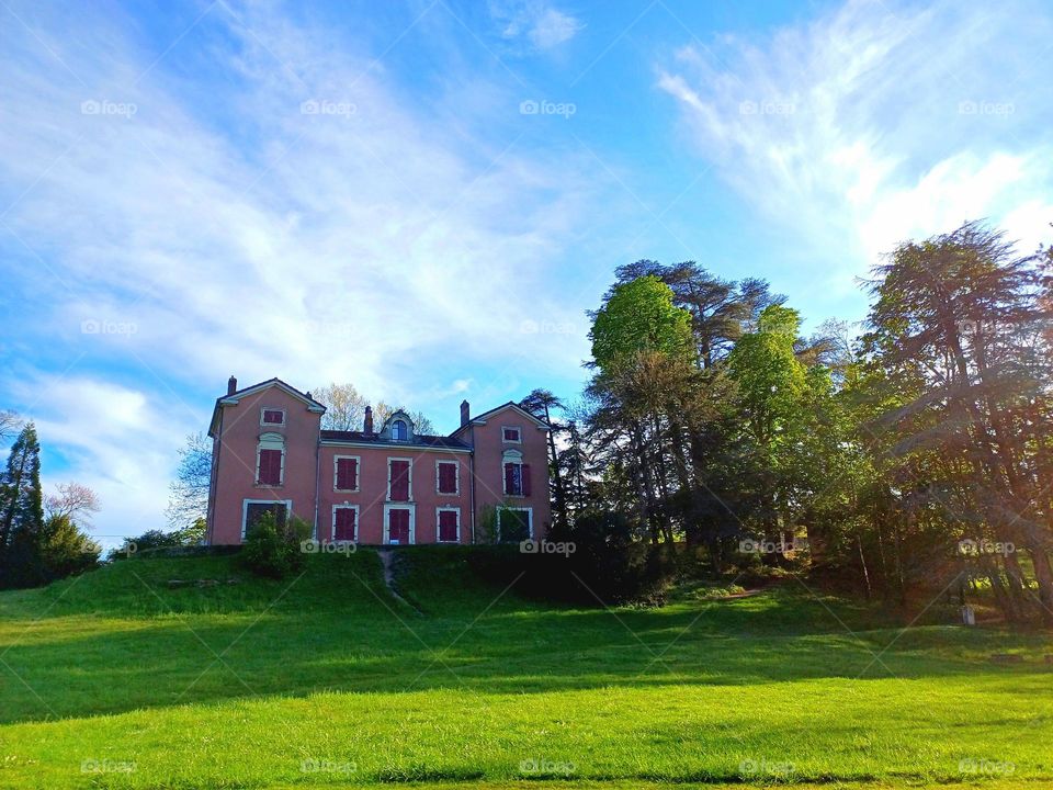 a pink manor in a green Park in france