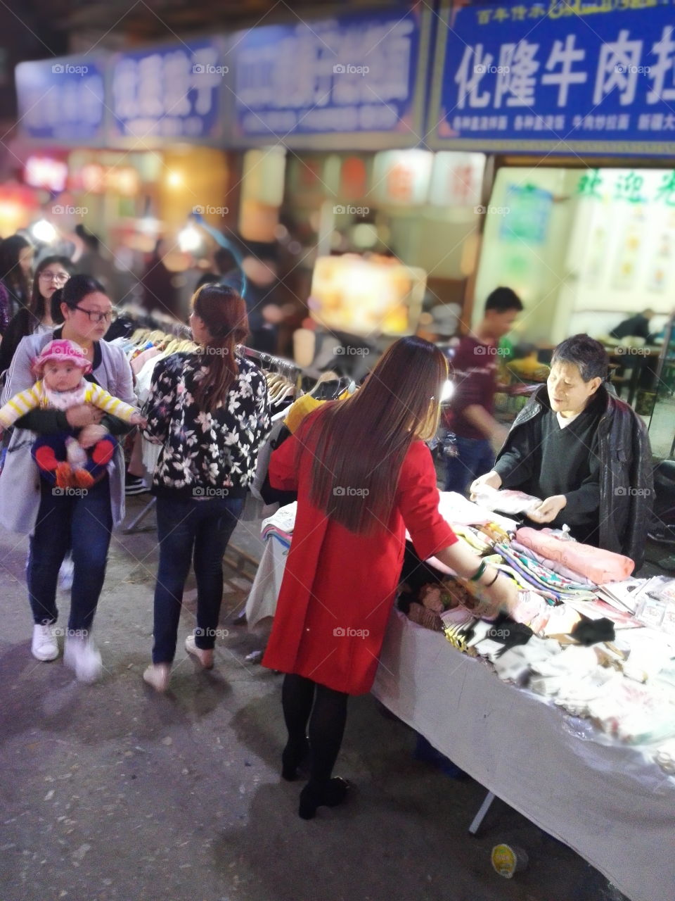 this photo was captured at night almost 9pm in xi'an city in China. It must be different from your city. It shows night life which some of people selling little things on the street to suppoer their life. most of people of living nearby this village enjoy shopping in there. it is cheaper to buy somethings you need than other stores or shopping mall. so i perfer to go shopping in there instead of mall or shopping center. when you are hungry, you also get foods there and enjoy it...
usually it starts from 8pm to 11pm. the girl with red cloth was looking for some socks she needs. maybe they were bargaining . haha....