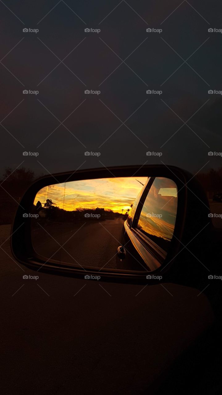 Mirror view inside car during sunset 